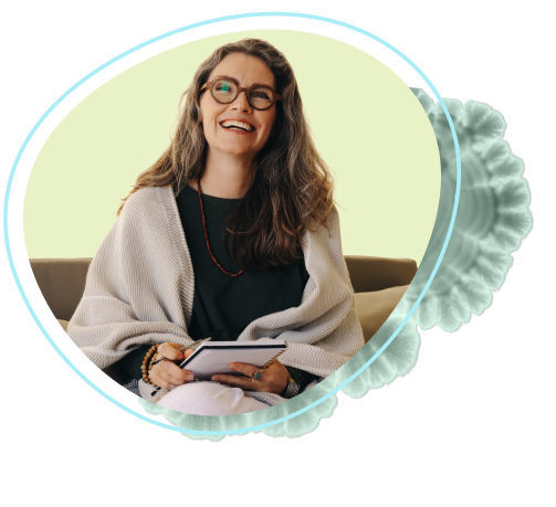 Woman smiling on couch with notebook.